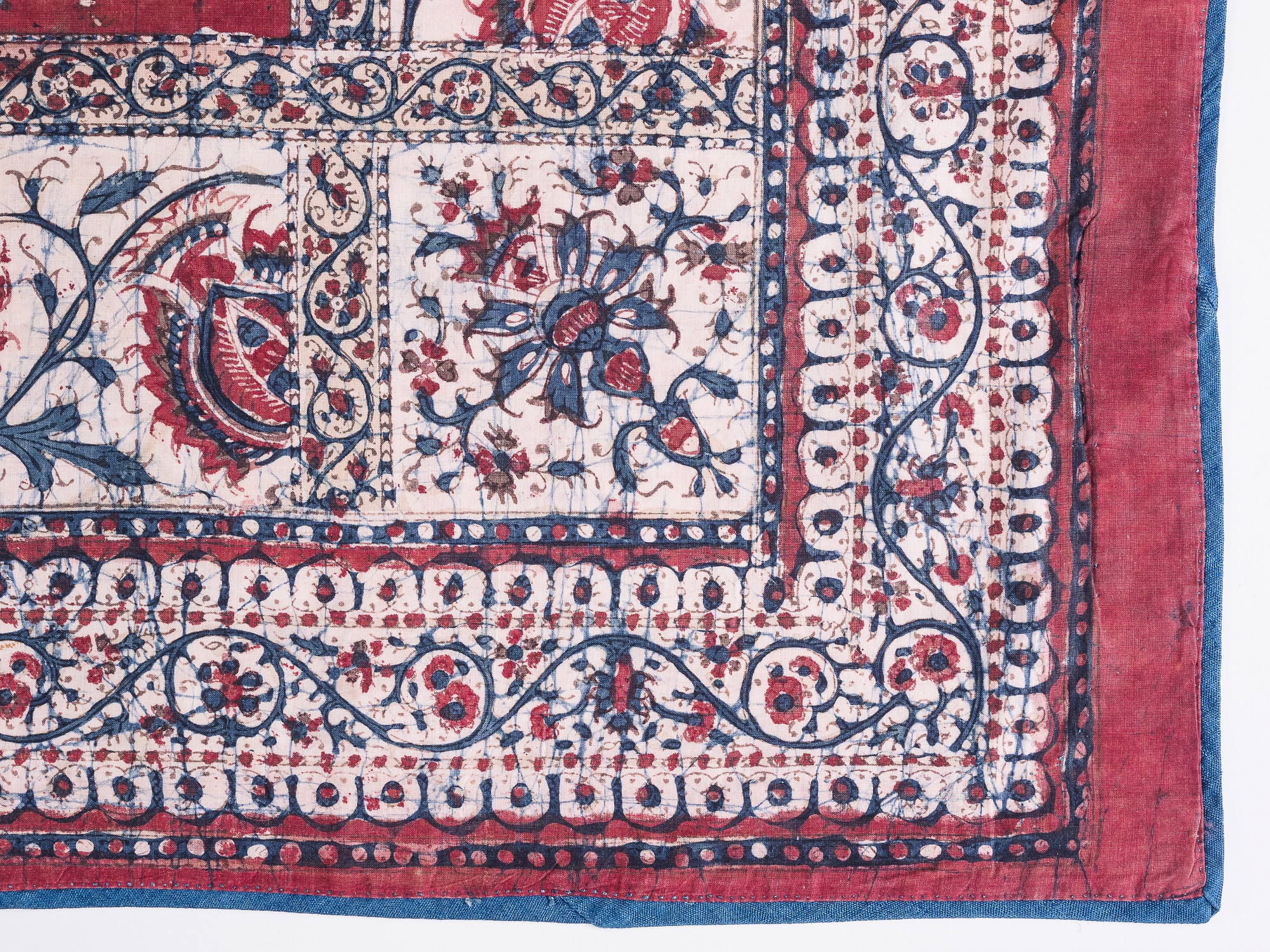 A number of print methods are evident on this furnishing fabric, likely created in India for the European market. The central square is roller printed while the surrounding band is batik: worked with a resist of resin and glue, then immersed in a vat of indigo dye. The smooth finish suggests that the fabric was glazed once printed and dying was complete.   Bought in Baghdad in 1960, created c.1880